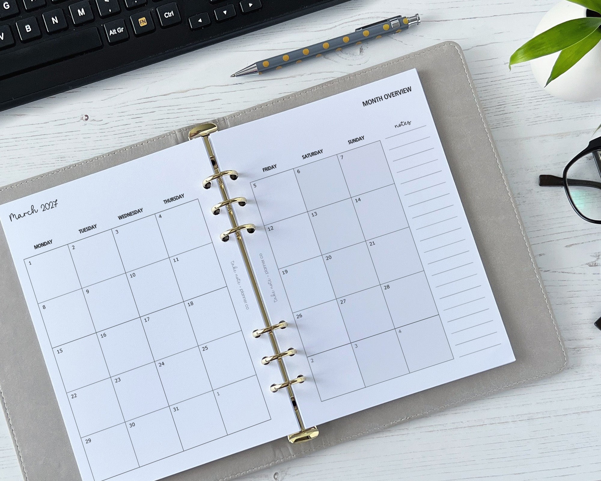 Calendar planner on a desk with a keyboard and pen in the background