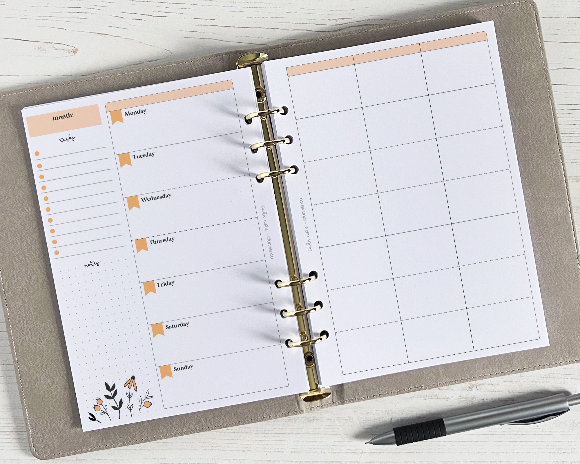 A floral design undated weekly planner insert with a golden spiral binding and space for weekly planning on a white background, accompanied by a pen and placed on a wooden surface.