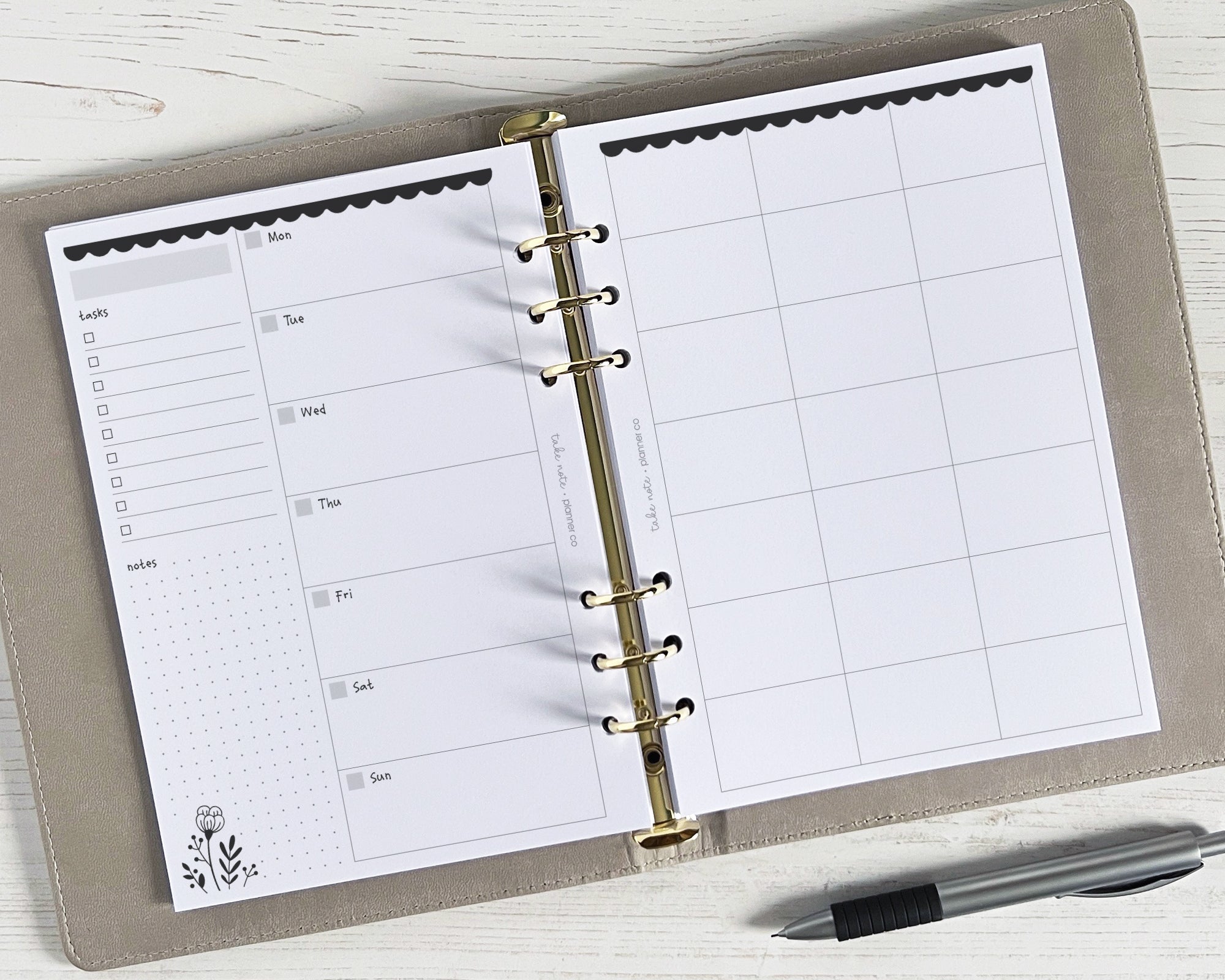A5 weekly planner inserts with a monochrome floral design, undated, displayed open on a desk with a pen alongside.