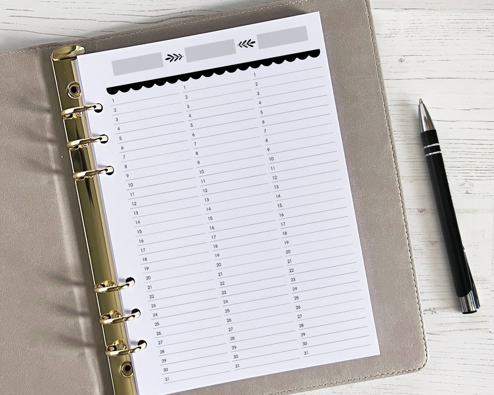 A photo of an undated quarterly overview insert for a planner, with a floral design. The insert is placed inside a binder, and a pen is visible next to it on the desk.