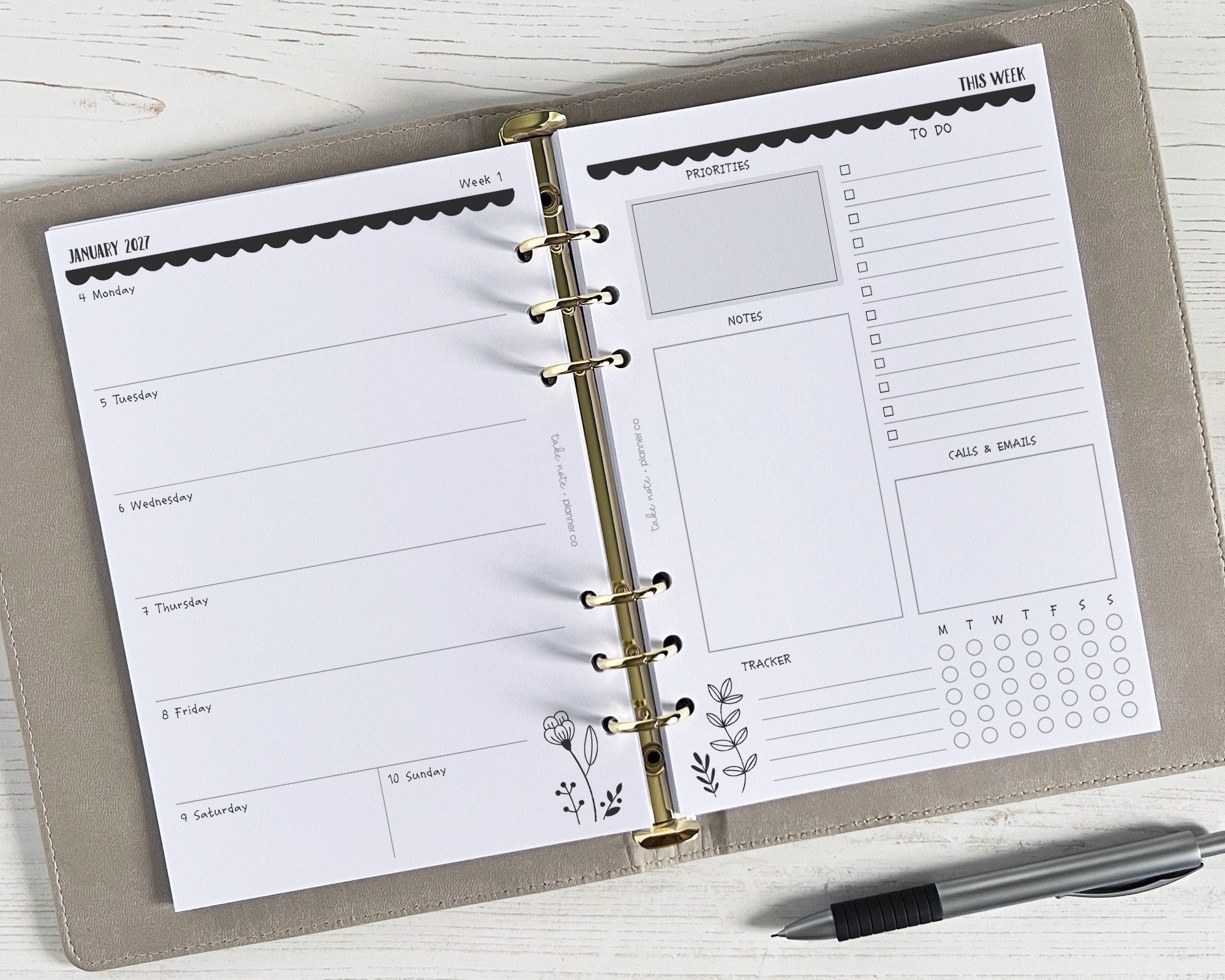 A5 weekly planner inserts with a monochrome floral design, displayed in a ring binder with a pen for scale.
