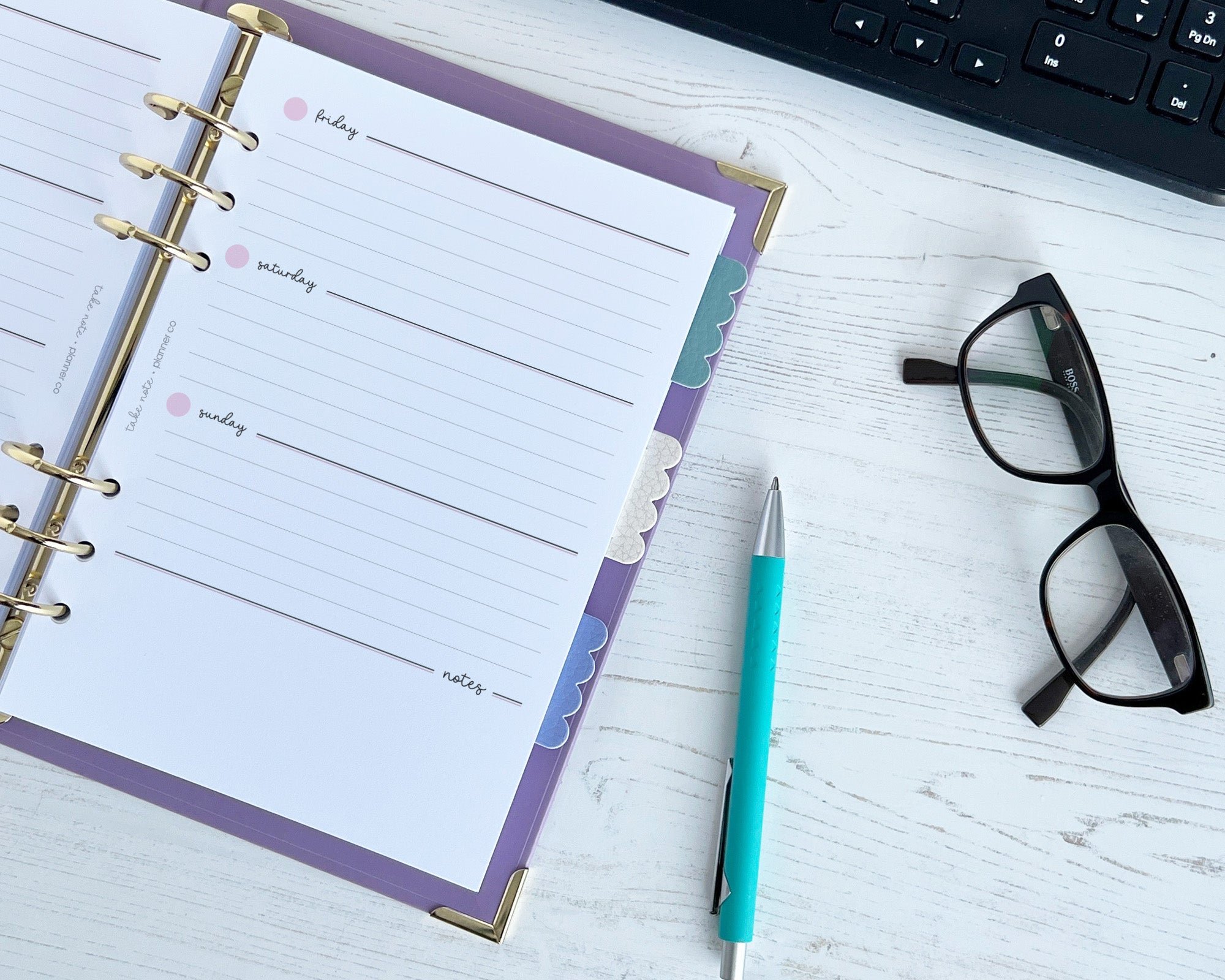 Planner with a pen and glasses on a desk with scallop shaped bookmarks