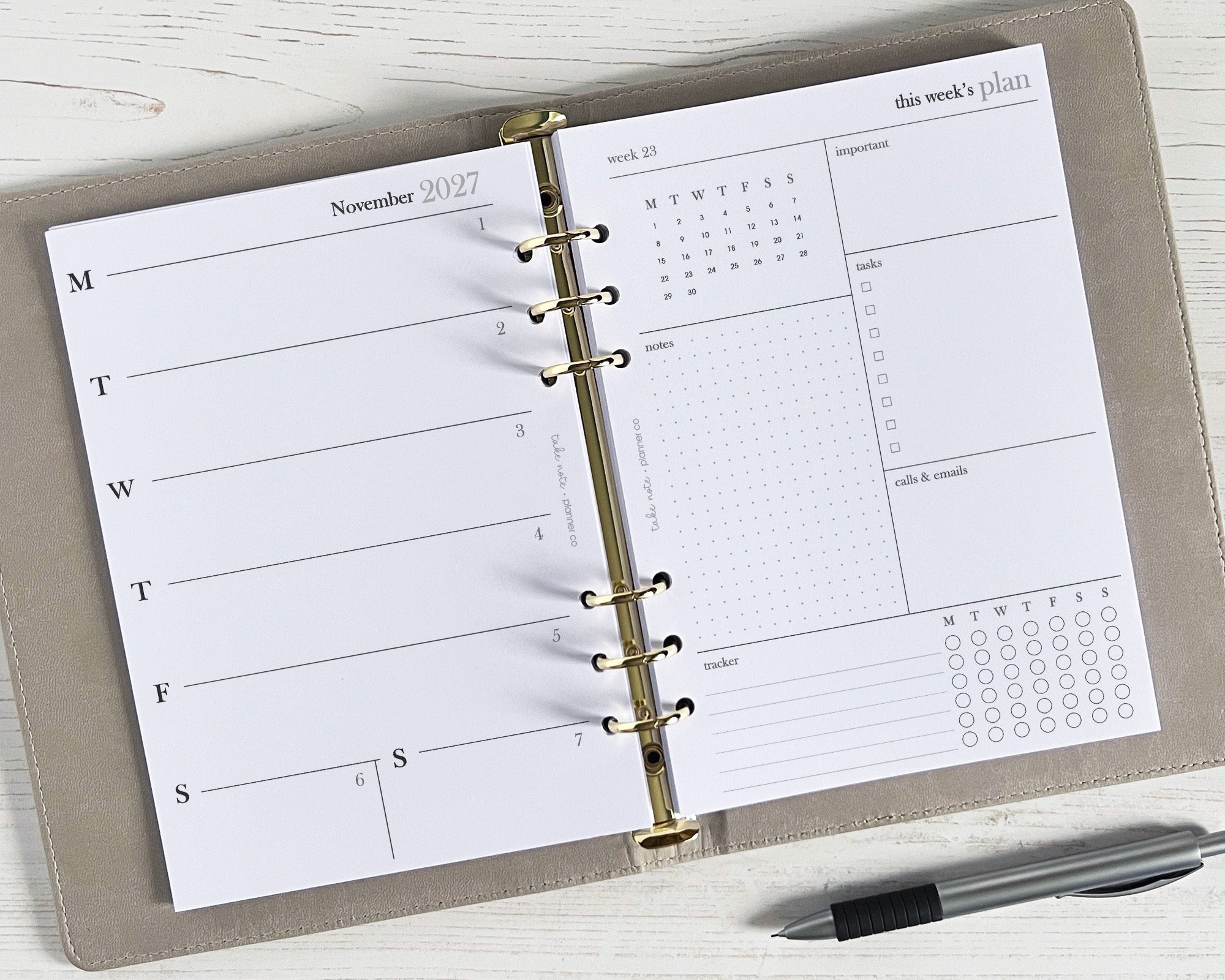 A weekly planner insert with a simple, minimal design, featuring spaces for notes, appointments, and a tasks page, displayed open on a desk with a pen beside it.