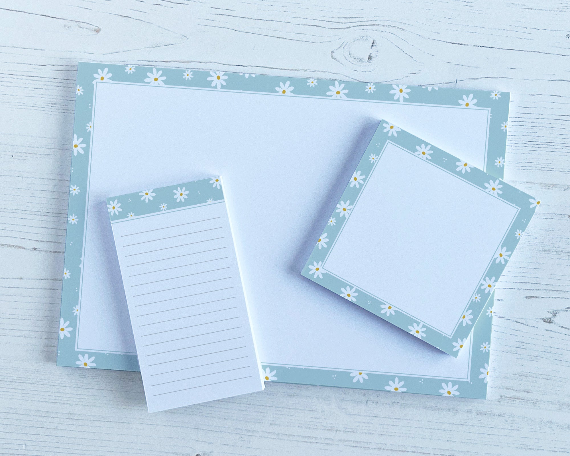 Set of stationery items with floral border on a light wooden surface