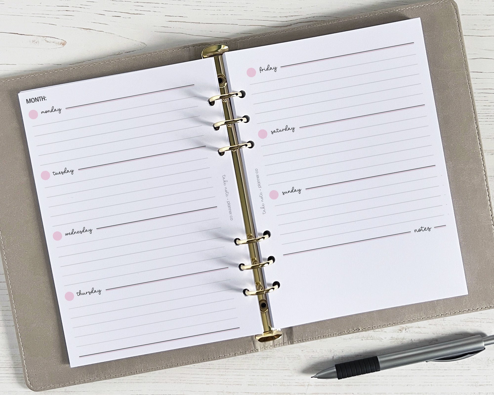 A5 weekly planner inserts displayed open with lined pages and space for notes, undated, with a pen beside them.