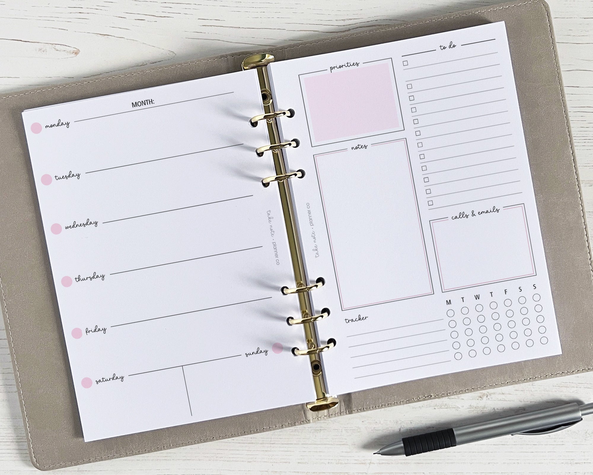 A5 weekly planner inserts with a classic design, undated, displayed open on a desk with a pen alongside. The pages include sections for schedule/appointments, notes, to-dos, and a habit tracker.