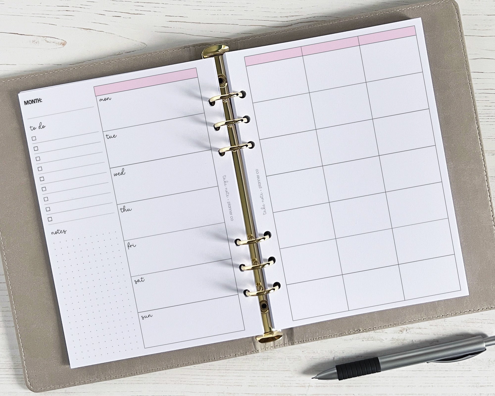 An open weekly planner insert with a classic design, showing a monthly view with spaces for notes, and a pen resting beside it.