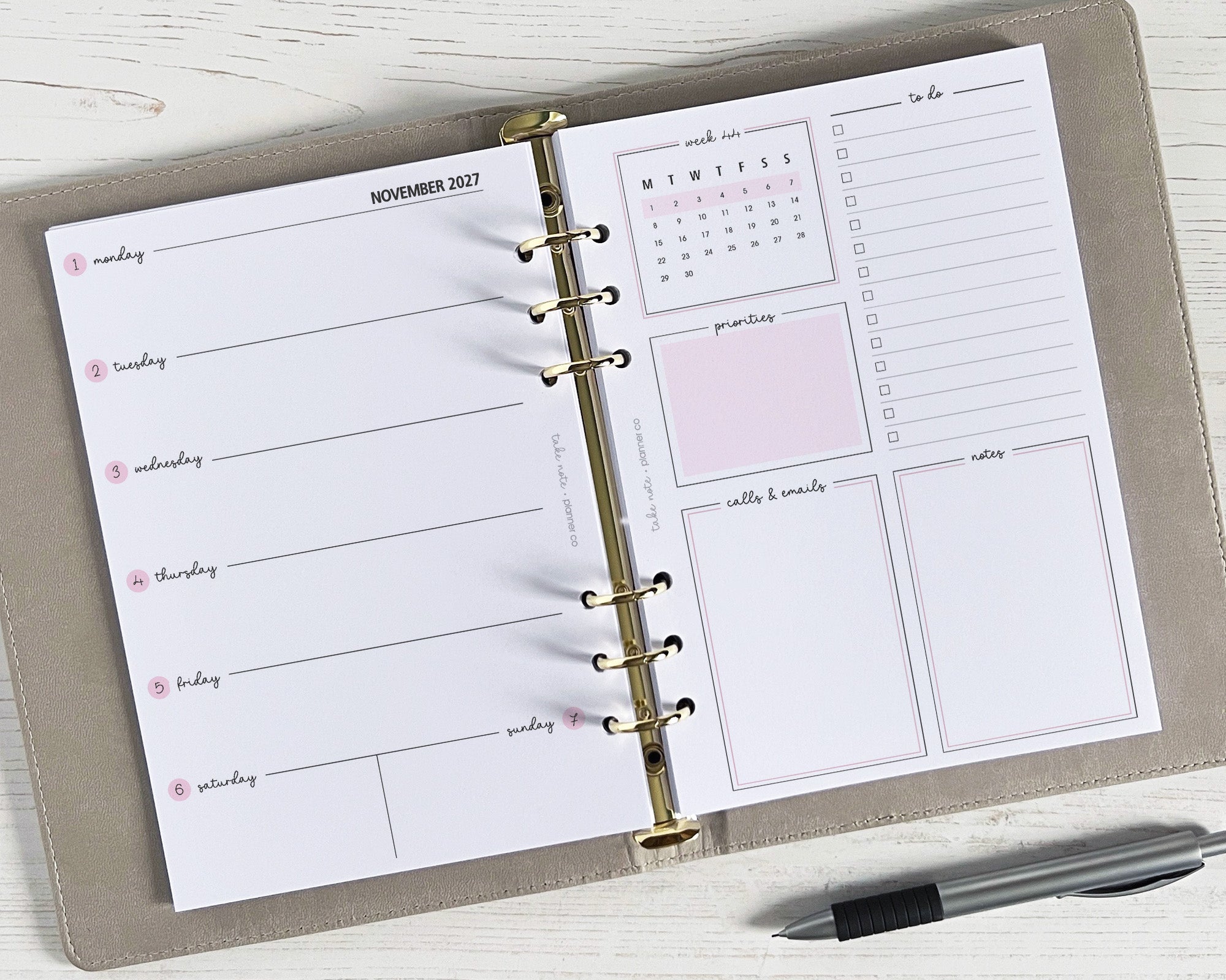 A weekly planner insert with a classic design, featuring spaces for notes, appointments, and a tasks page, displayed open on a desk with a pen alongside.