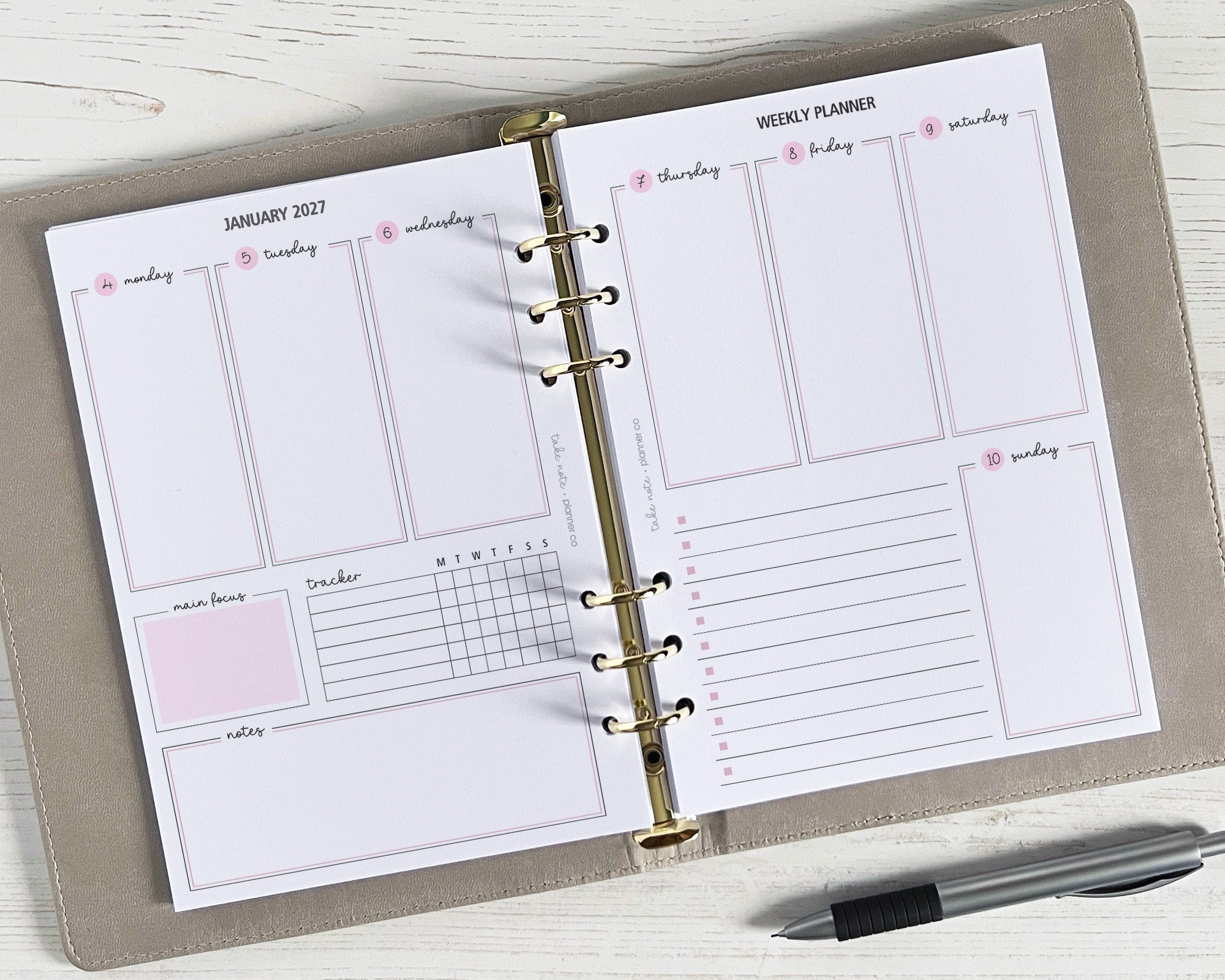 A5 weekly planner inserts displayed open on a desk with a pen alongside. The planner includes spaces for daily schedules, notes, to-do lists, and a habit tracker.