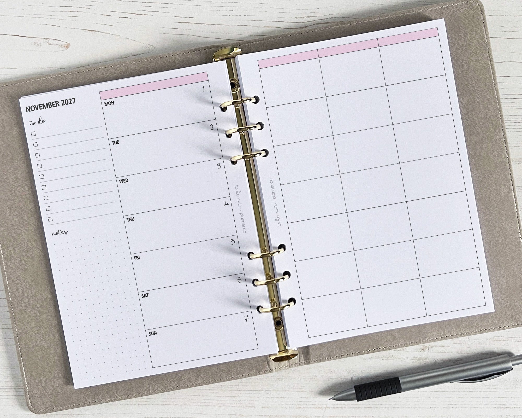 A5 weekly planner inserts displayed open on a desk with a pen alongside. The pages show a weekly spread with space for notes and appointments.