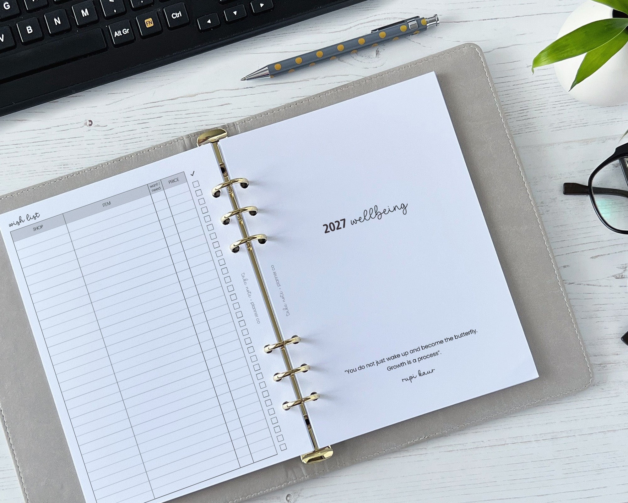 Open planner on a desk with keyboard and glasses