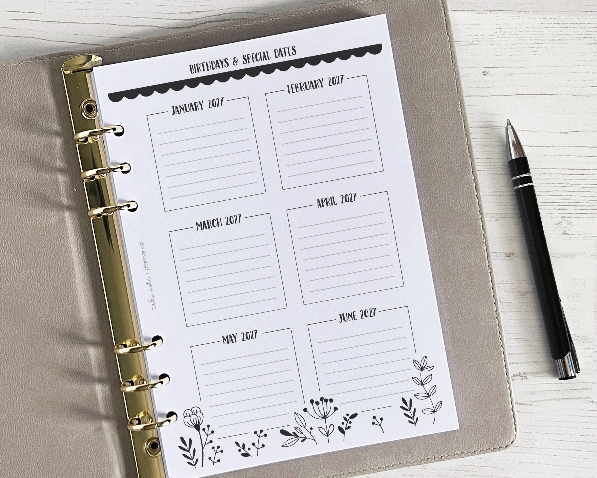 A yearly overview insert with a monochrome floral design, featuring spaces for writing in a planner, accompanied by a pen.