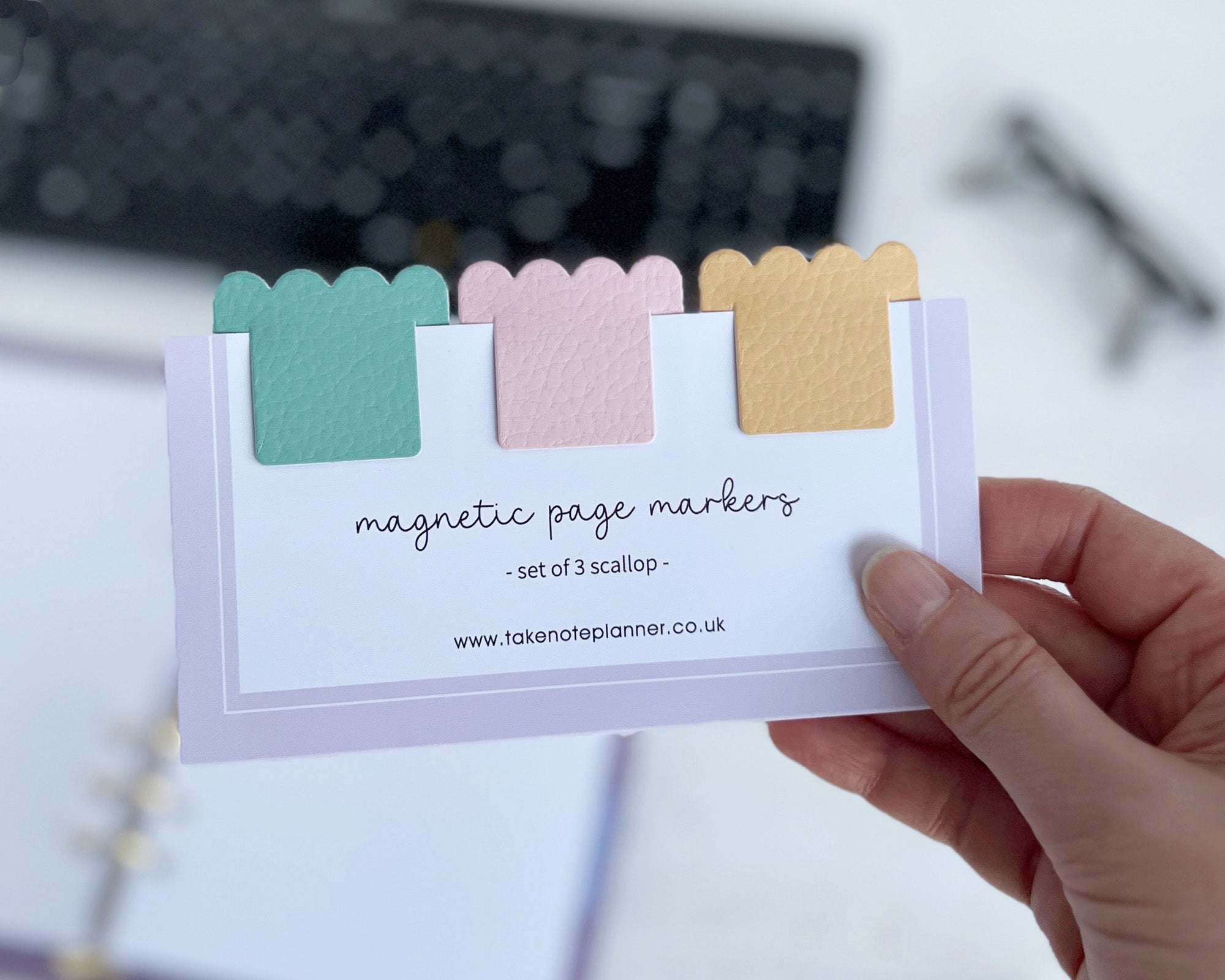 Set of three colorful magnetic page markers on a card held by a hand.