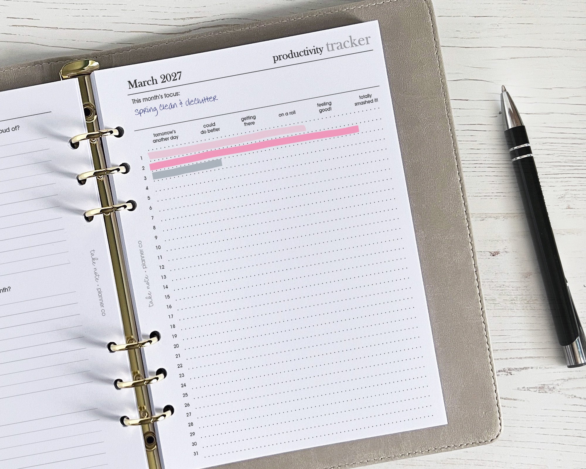 Productivity tracker in a planner with a pen on a wooden surface