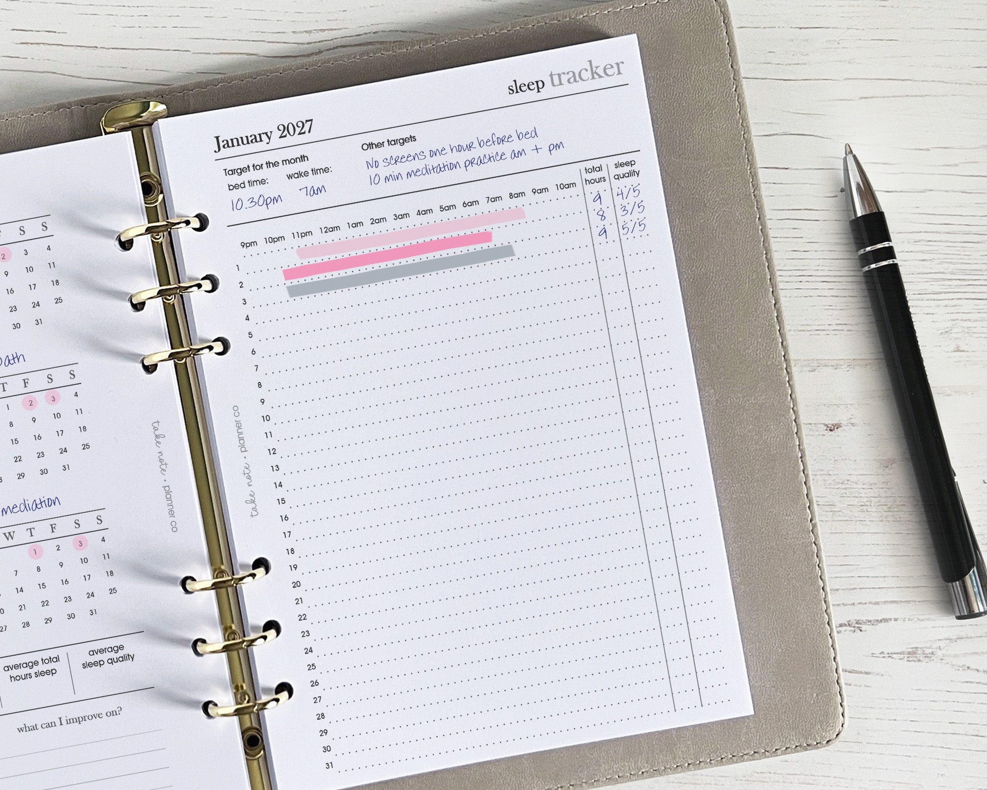A sleep tracker insert placed inside an organizer or planner, with a pen beside it, on a wooden desk surface. The insert has a minimalistic design featuring text and checkboxes.