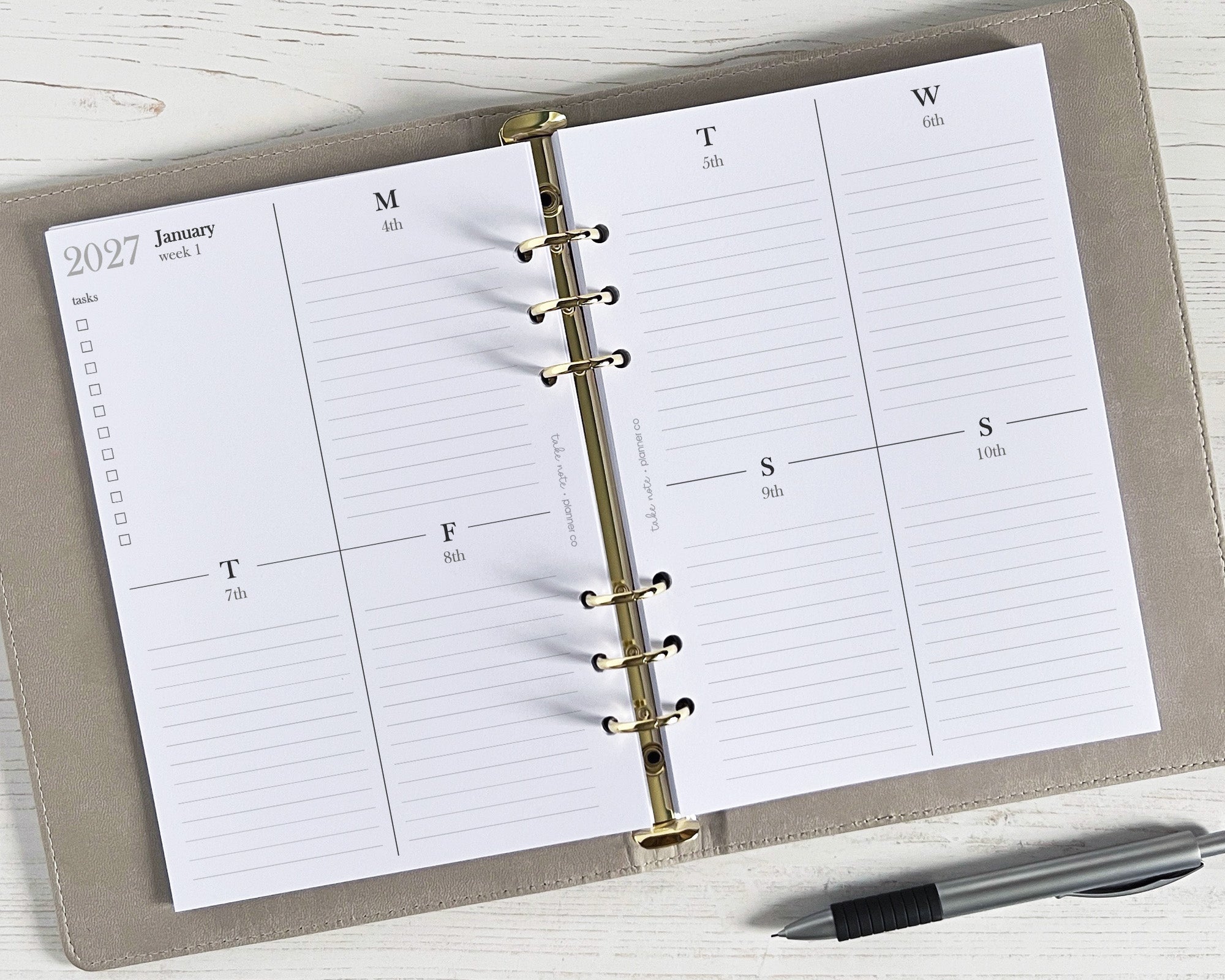 A5 weekly planner inserts displayed open on a desk with a pen alongside, showing a minimalistic design with space for weekly appointments and notes.