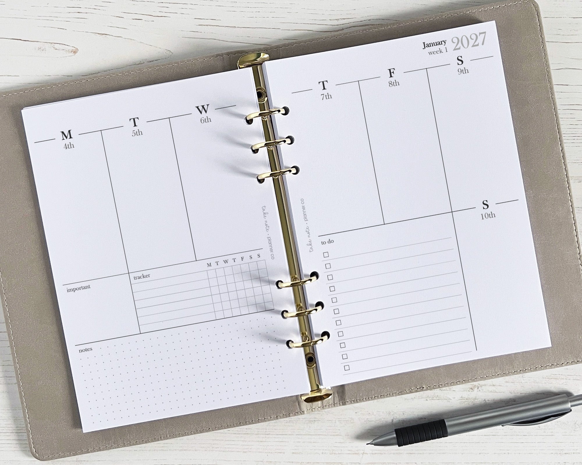 A weekly planner insert with a simple, minimal design, displayed open on a desk with a pen beside it.