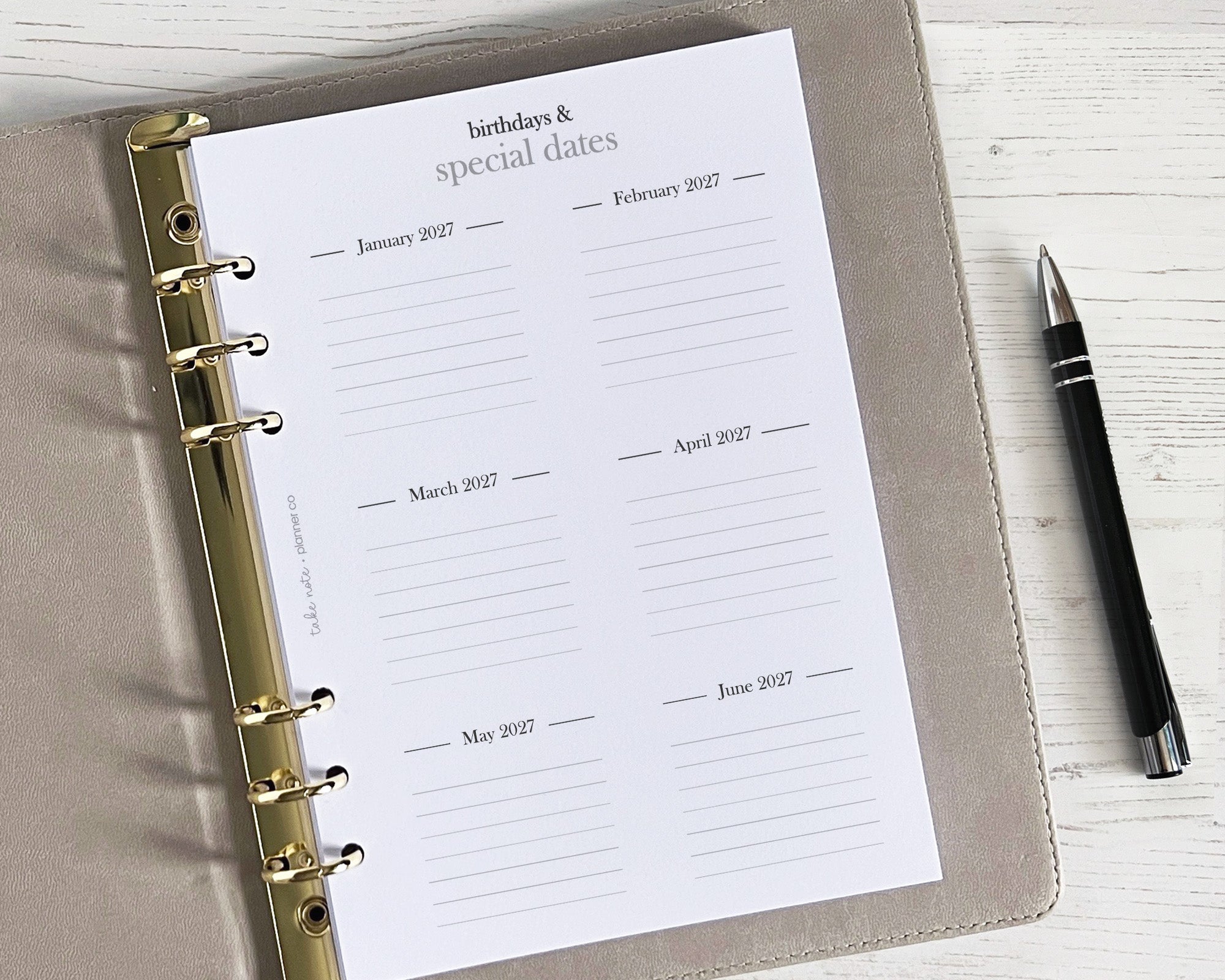 A yearly overview insert sheet with a minimalistic design, displayed in an open planner. A pen is placed to the side of the sheet.