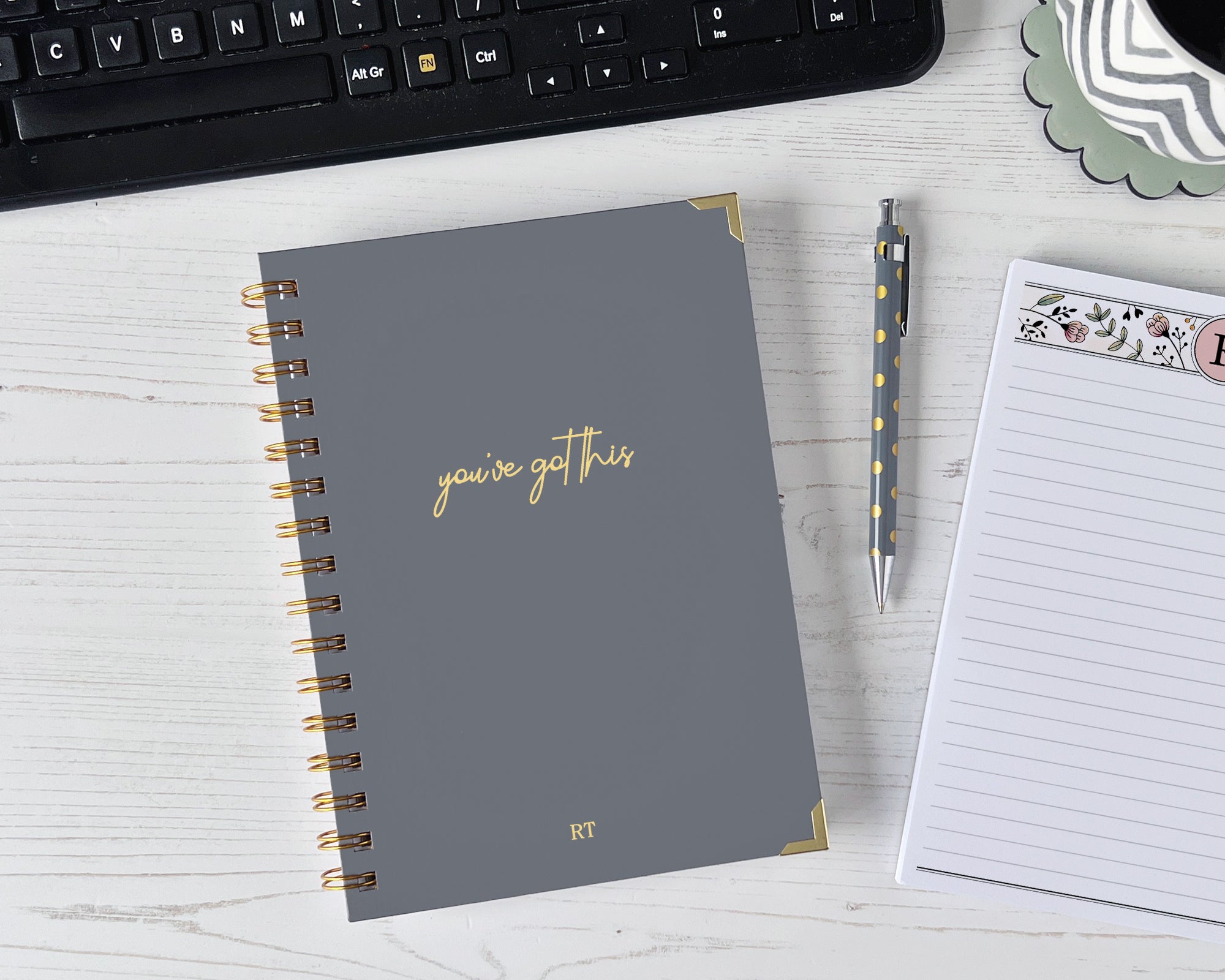 Gray notebook with 'you've got this' text on a desk with a keyboard and pen.