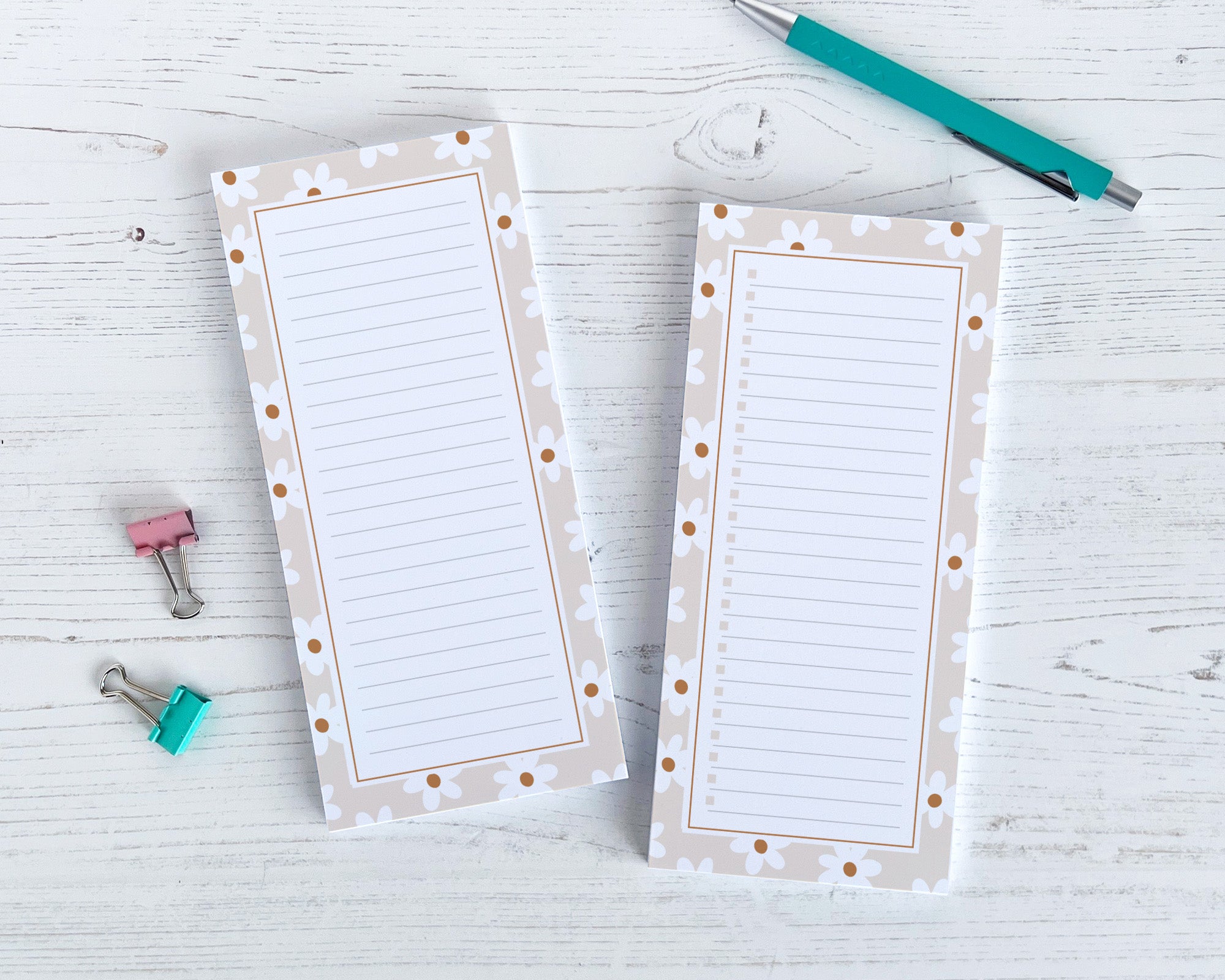 Two lined notepads with decorative borders on a light wooden surface with stationery items.