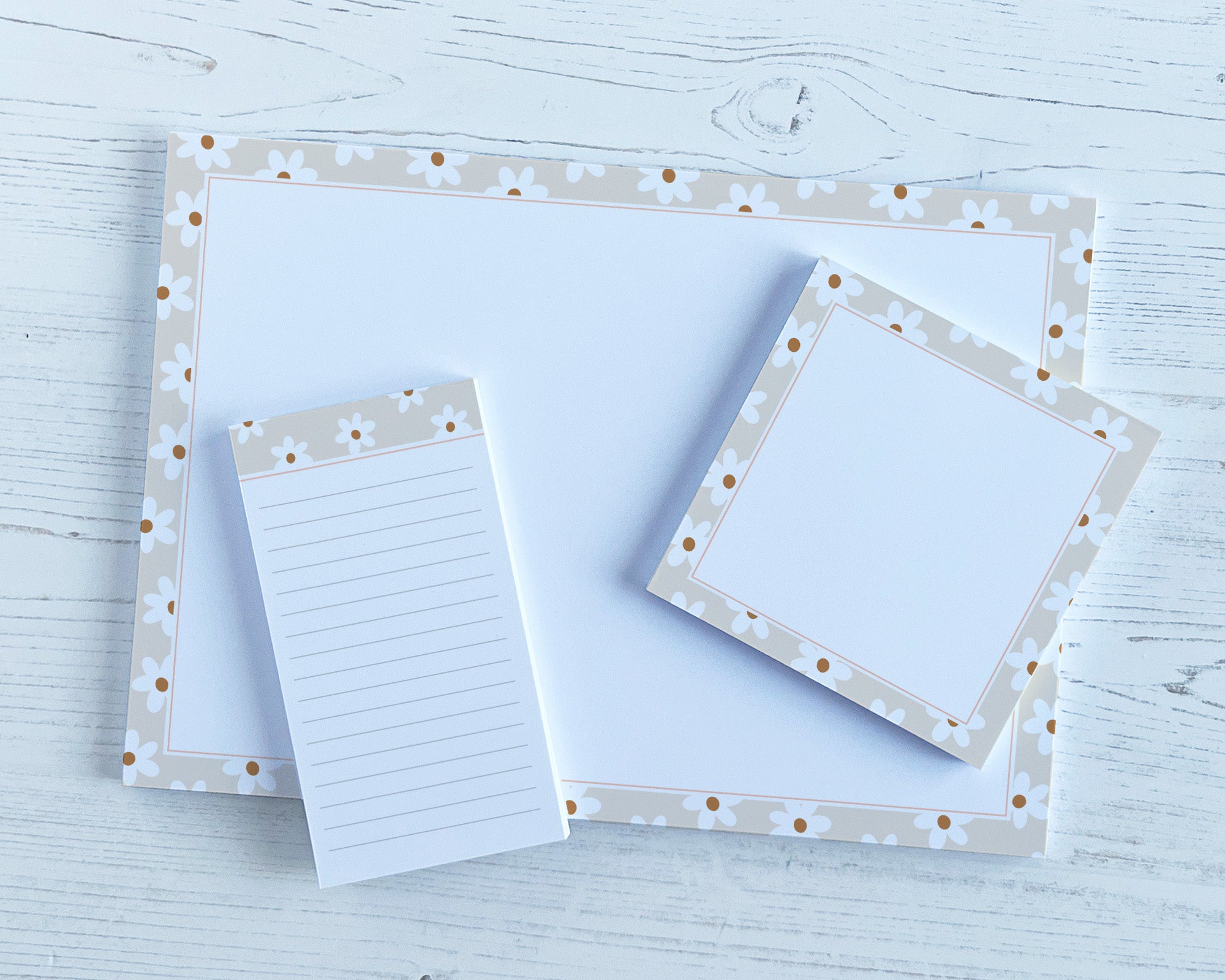 Set of stationery items with decorative floral borders on a light wooden surface